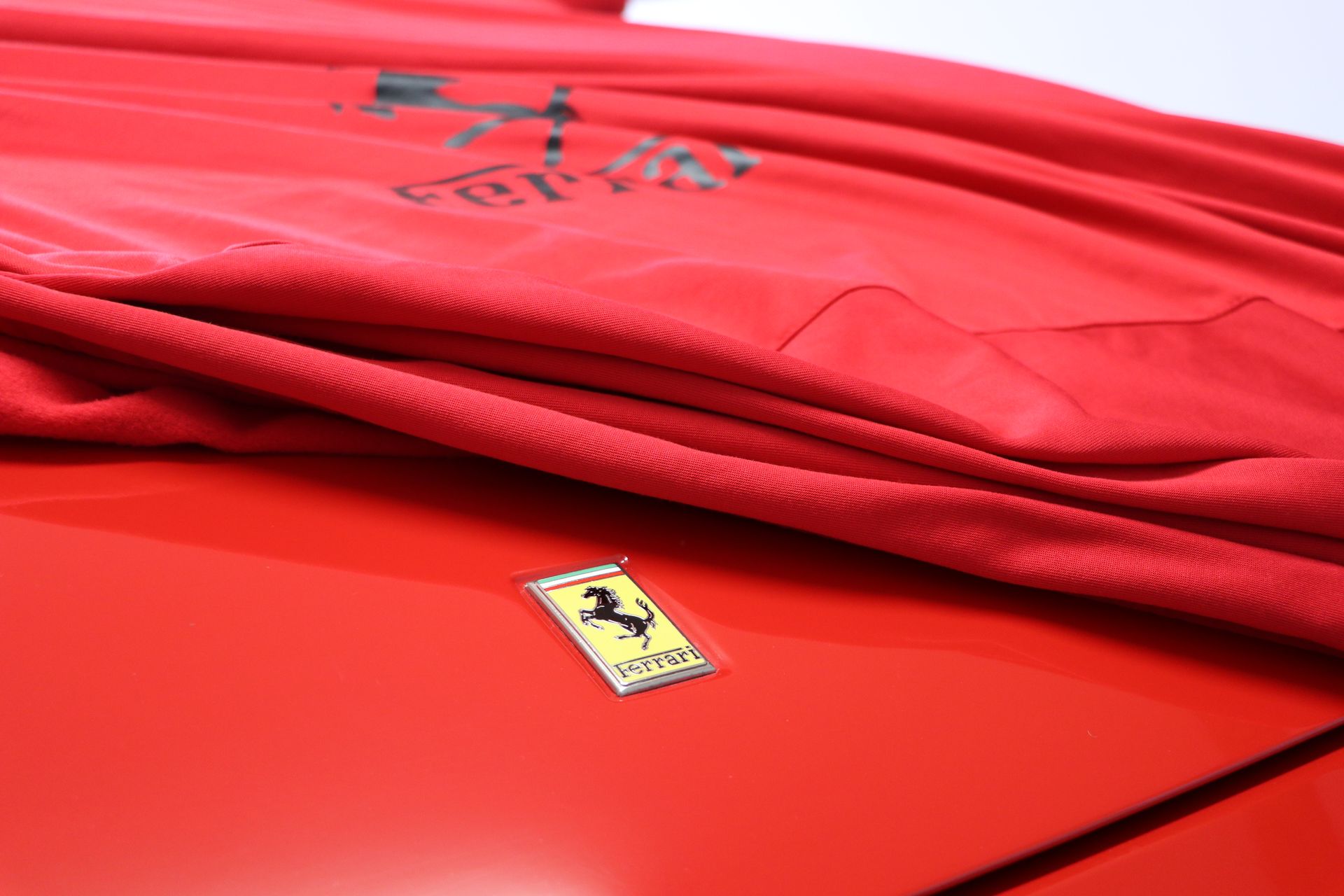 Red Ferrari with red car cover across bonnet 