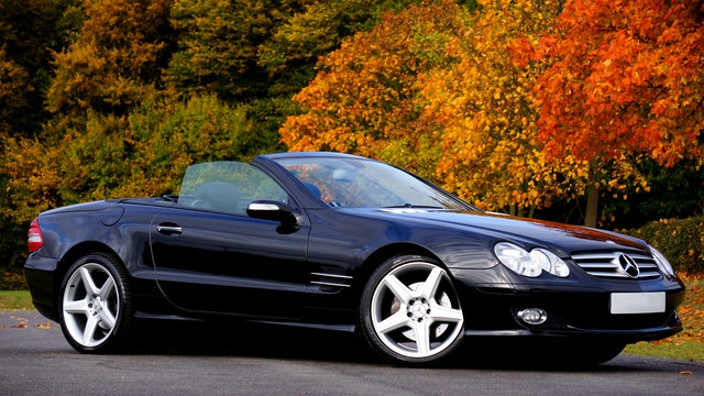 Black Mercedes SL in front of hedge row 