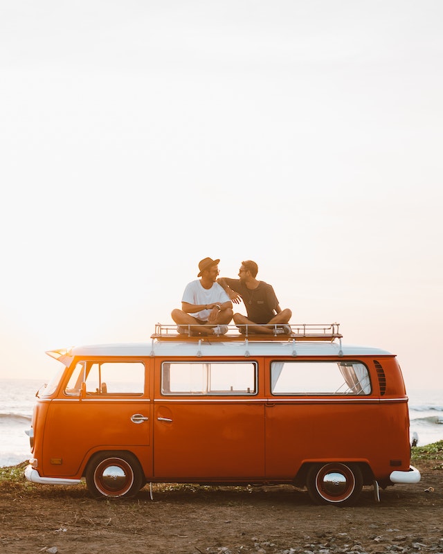 Orange VW camper in the sunset with two friends 